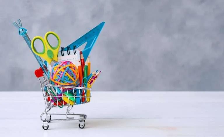 multi colored school supplies shopping cart gray background with copy space text concept returning school new school year shopping scaled