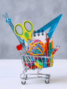 multi colored school supplies shopping cart gray background with copy space text concept returning school new school year shopping copy